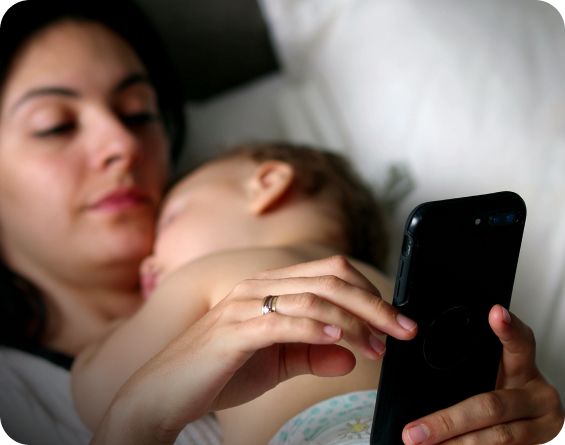 Mother holding a baby while looking at a phone