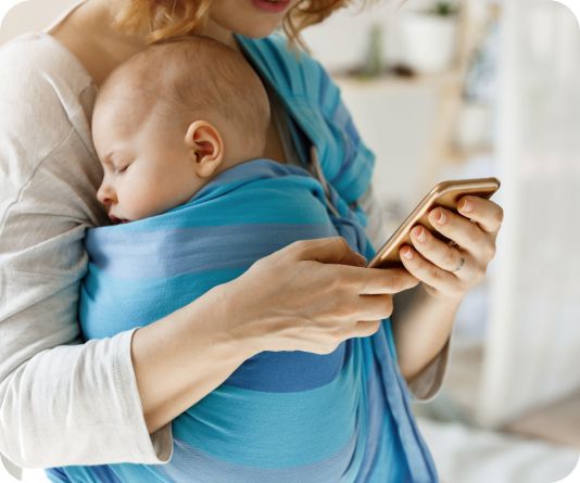 Mother holding a baby while looking at a phone